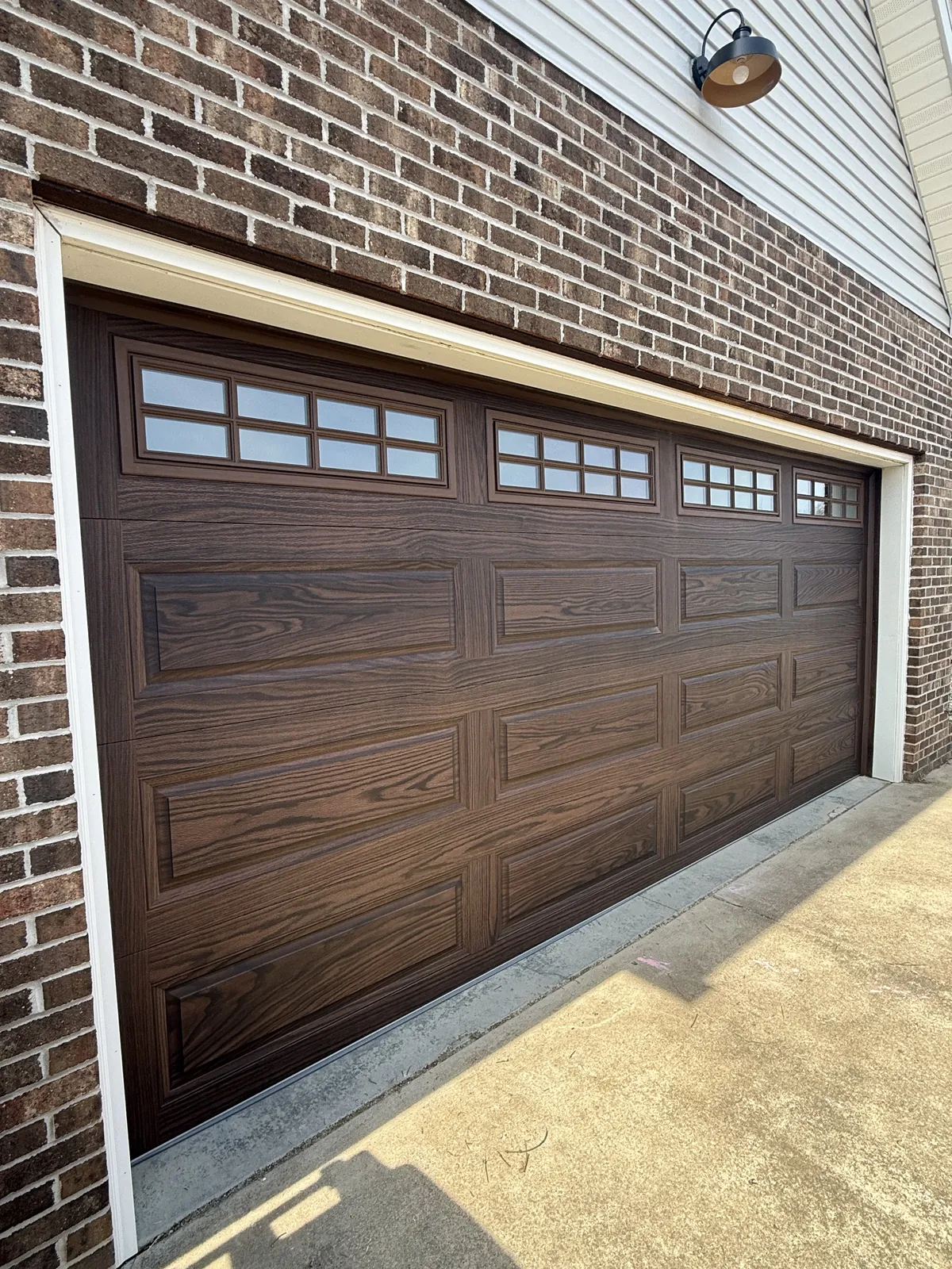 Casey Hogan garage after — A tired opening upgraded to warm woodgrain CHI doors that frame the brick.
