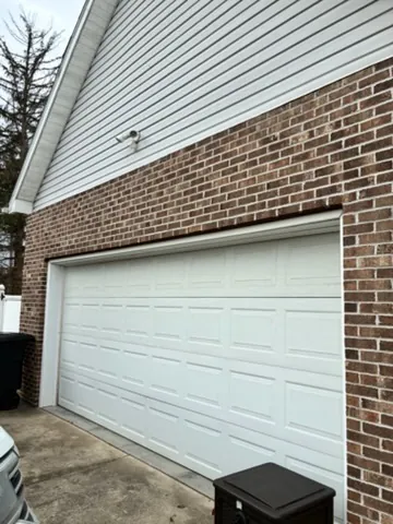 Casey Hogan garage before — A tired opening upgraded to warm woodgrain CHI doors that frame the brick.