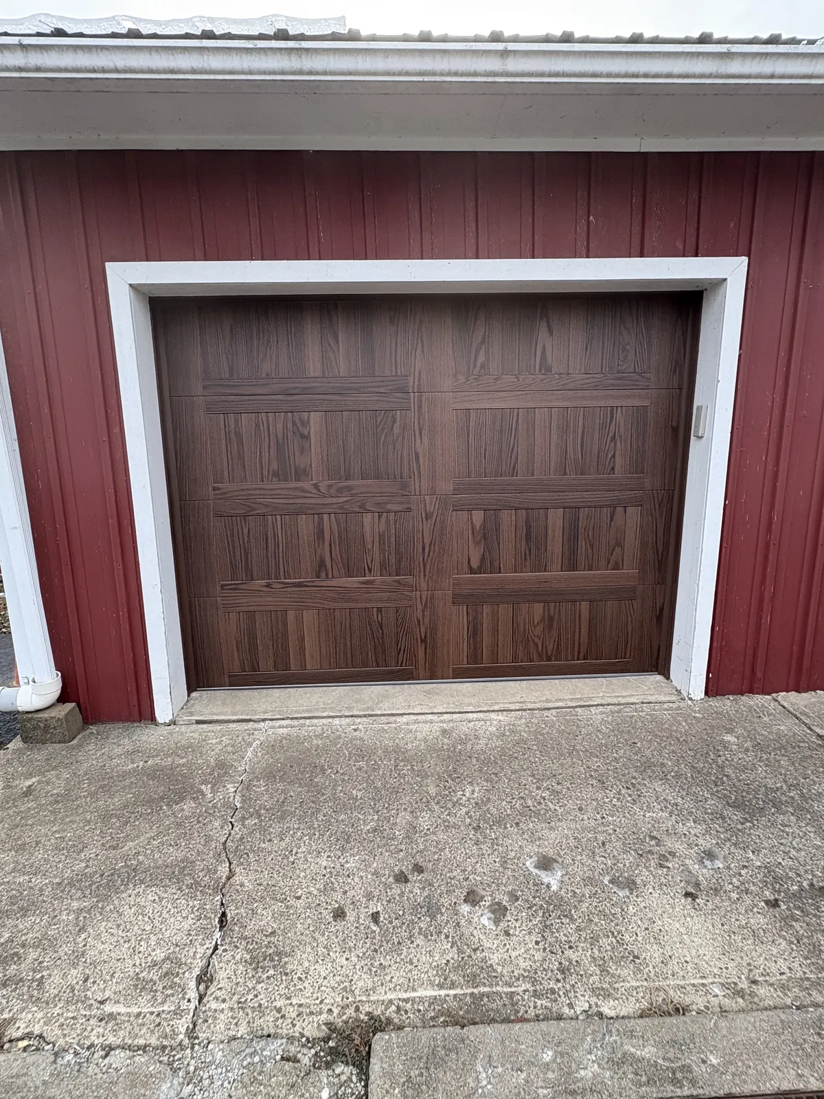 Frank Wise garage after — Faded white doors on a red barn, reborn as rich woodgrain CHI carriage doors.