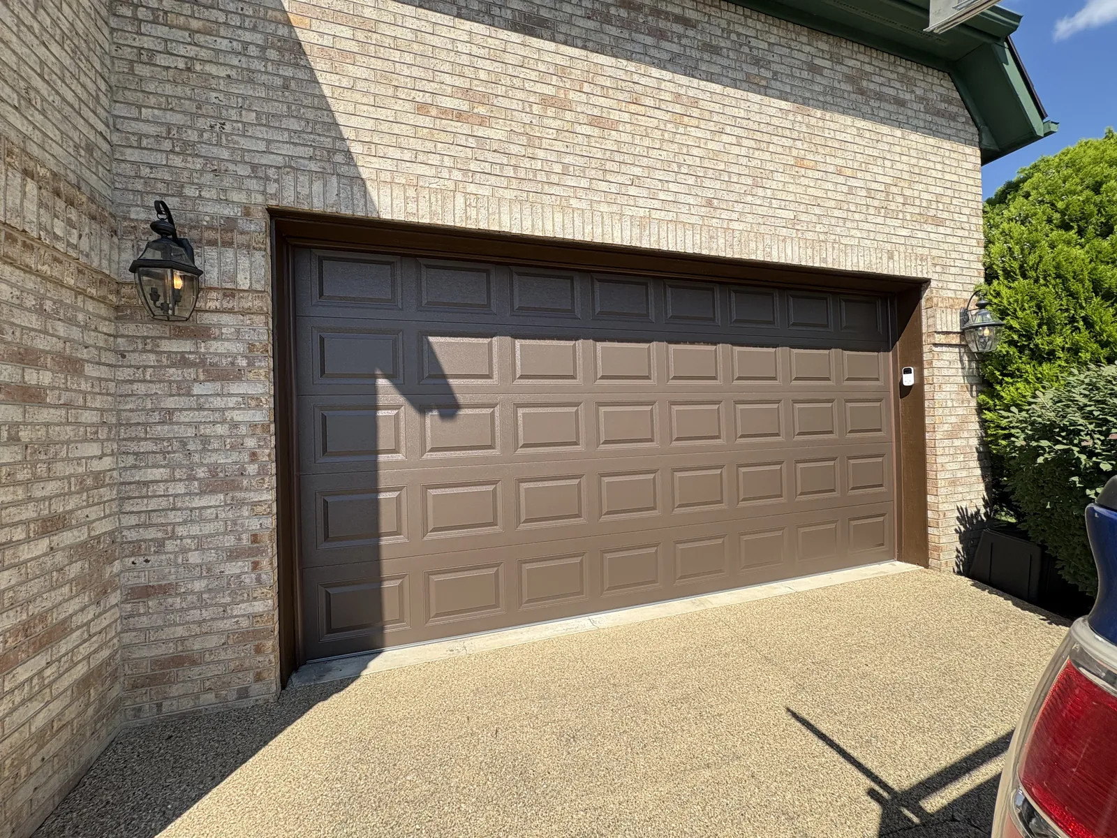 Kristi Evans garage after — Dated doors replaced with woodgrain CHI doors and crisp new brown trim.