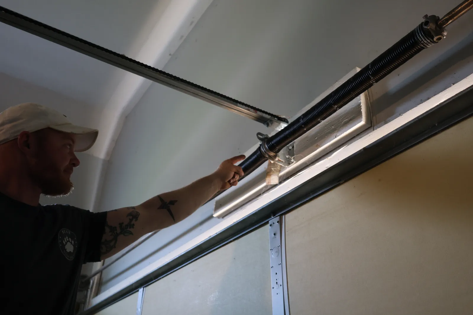 A Bear Door Services technician inspecting a torsion spring on site